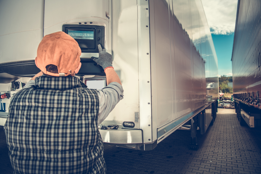 A logistics worker checking the temperature settings on a refrigerated transport truck.