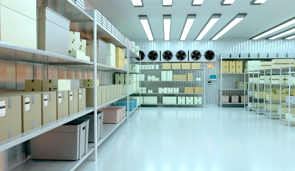 A modern temperature-controlled storage facility with organized shelves filled with boxes and cooling fans on the wall.